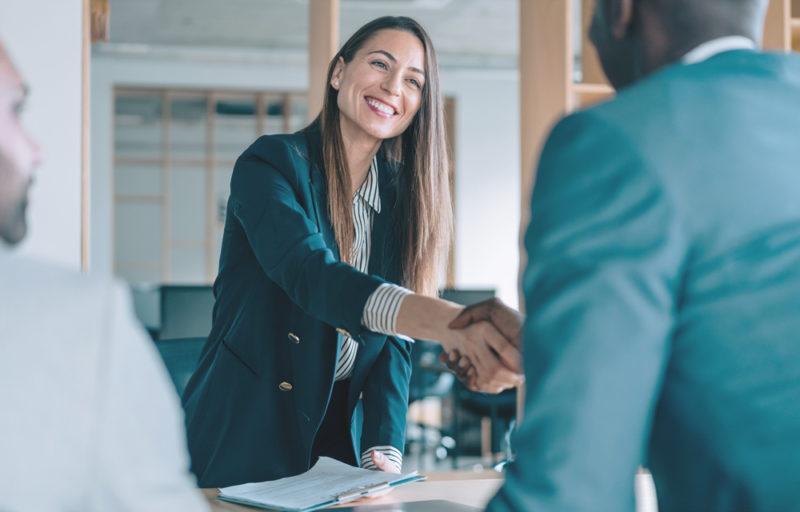 Smiling woman shakes hands with her counterpart